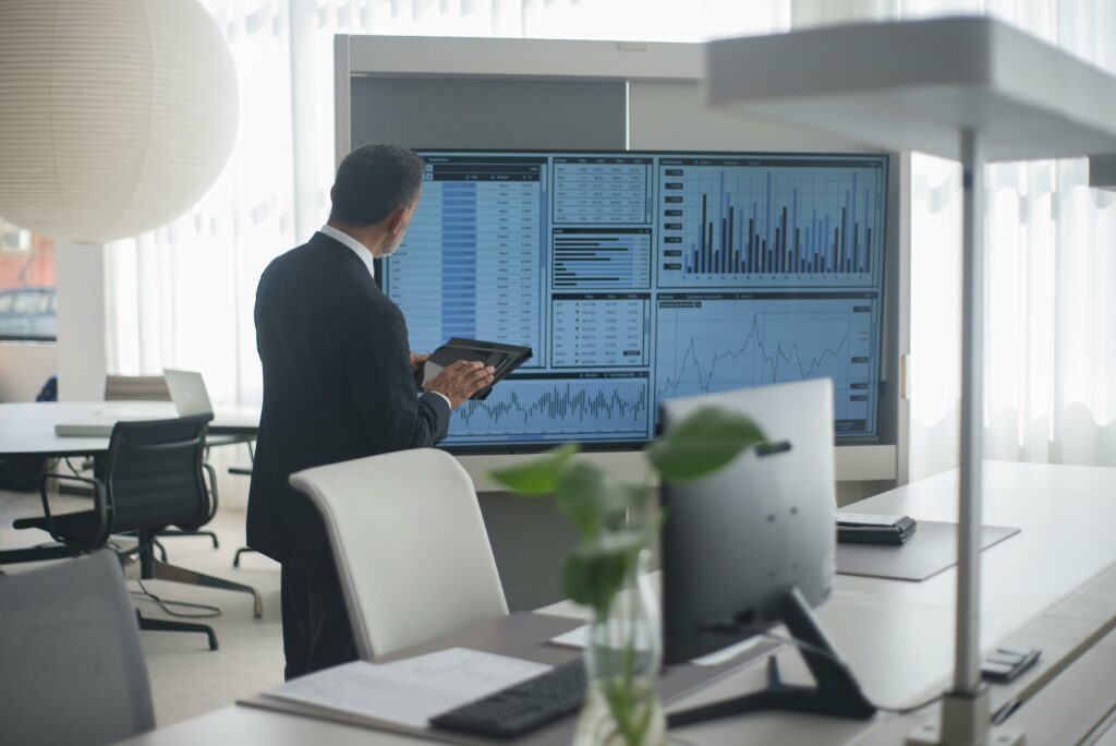 Professional in suit analyzing financial data on screens in a modern office setting.